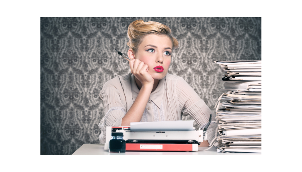 Photo d'une secrétaire vintage derrière une pile de dossier et une machine a écrire